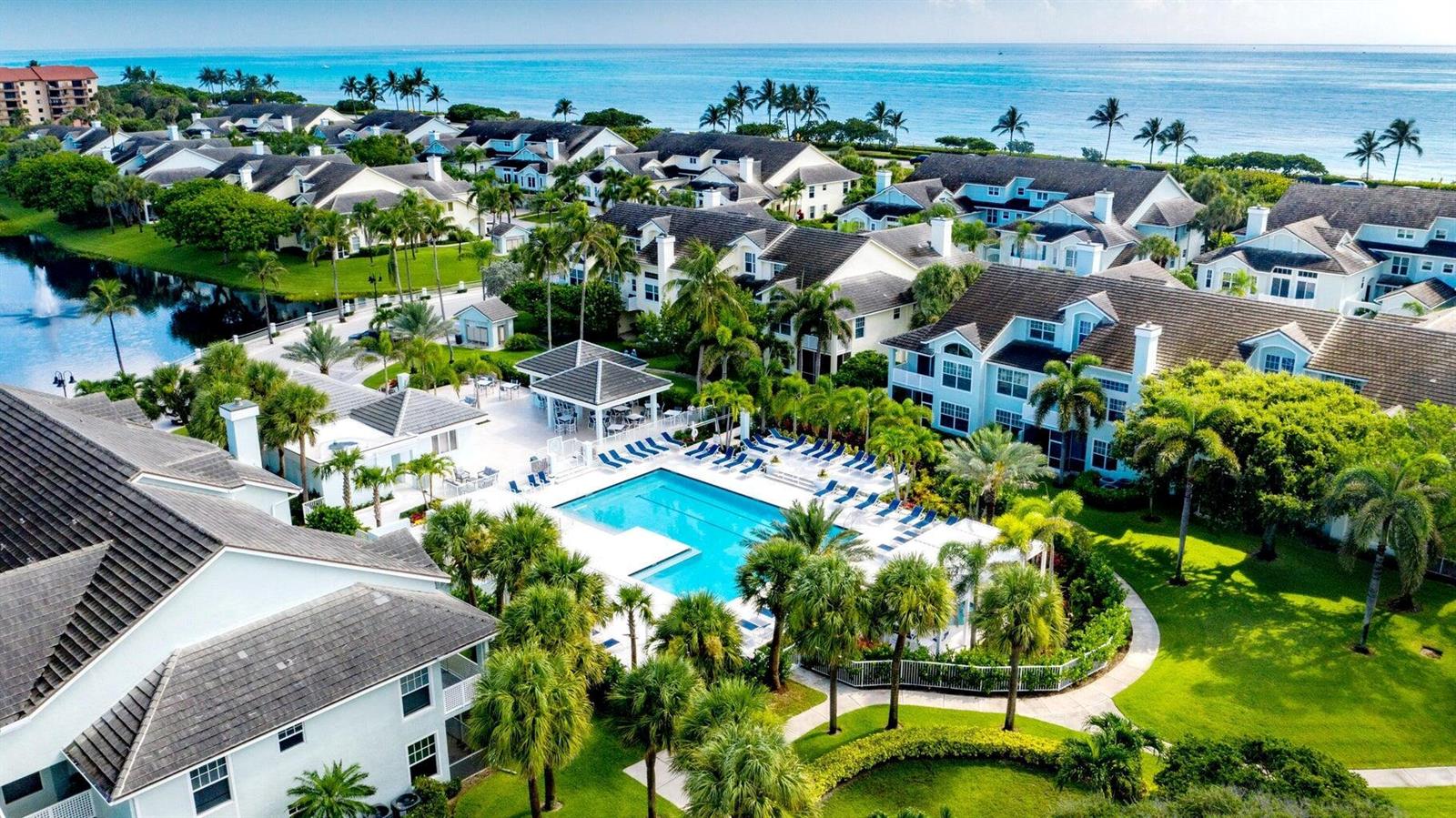 An aerial view shows a residential complex with a swimming pool, palm trees, and ocean — 207 Mainsail Circle, Jupiter FL 33477, JUPITER, FL