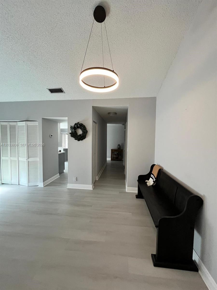 A living area features light wood-look flooring, a modern circular pendant light, and a bench — 3931 SW 84th Ter, Davie FL 33328, DAVIE, FL