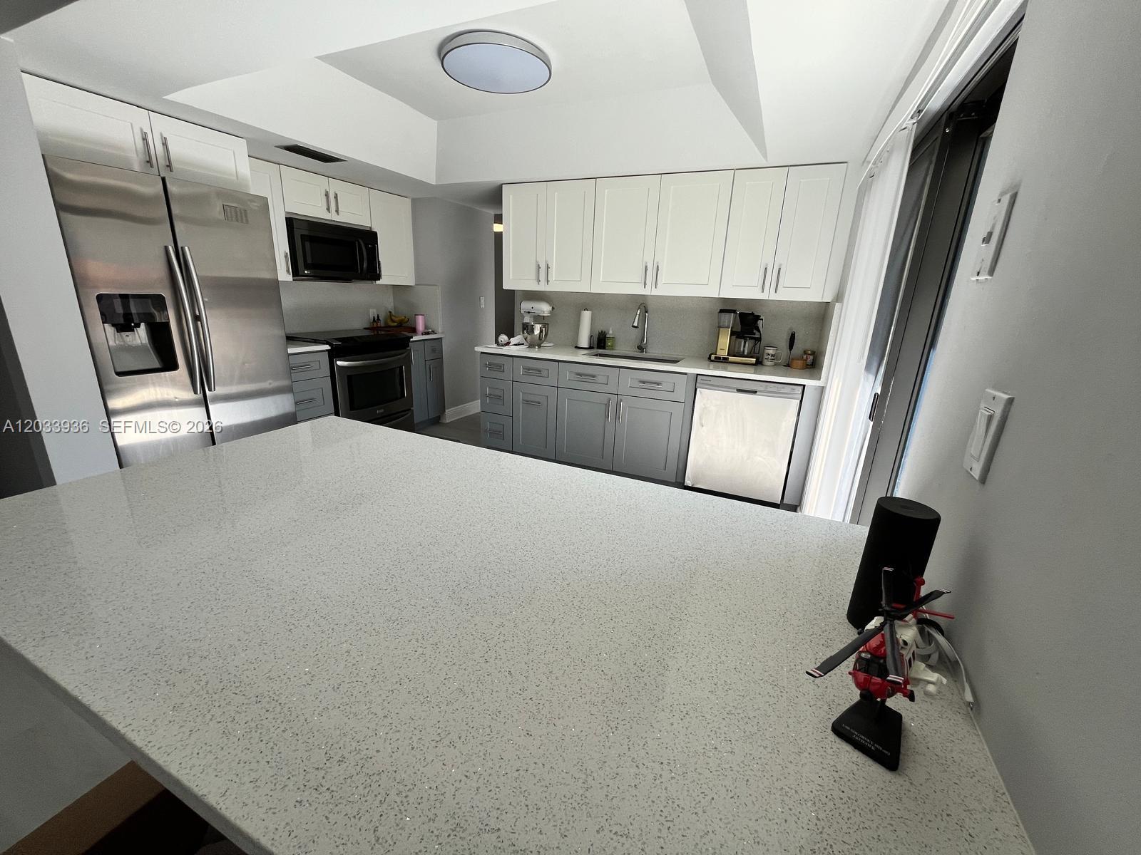 A kitchen features a large gray quartz island, two-tone cabinetry, and stainless steel appliances — 3931 SW 84th Ter, Davie FL 33328, DAVIE, FL