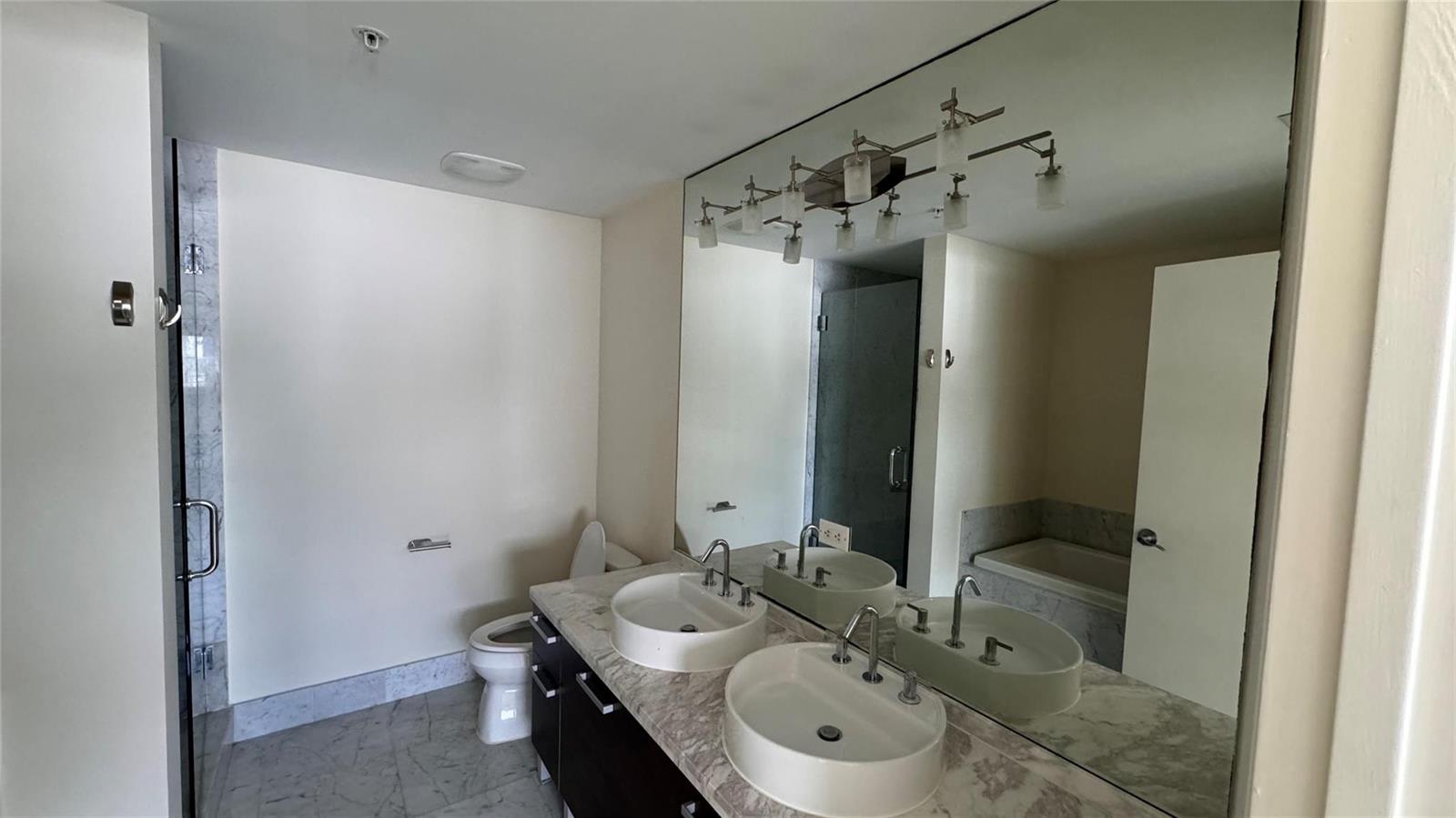 A bathroom features a double vanity with vessel sinks, marble countertops, and a large mirror — 253 NE 2nd Street # 3208, Miami FL 33132, MIAMI, FL
