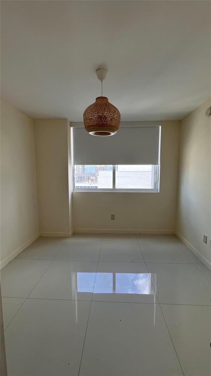 An empty room with white tile floors, beige walls, and a woven pendant light fixture — 253 NE 2nd Street # 3208, Miami FL 33132, MIAMI, FL