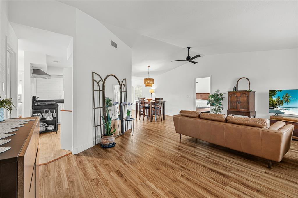 A living room and dining area with wood-look flooring, white walls, and a leather sofa — 2600 PALMETTO STREET, NOKOMIS, FL