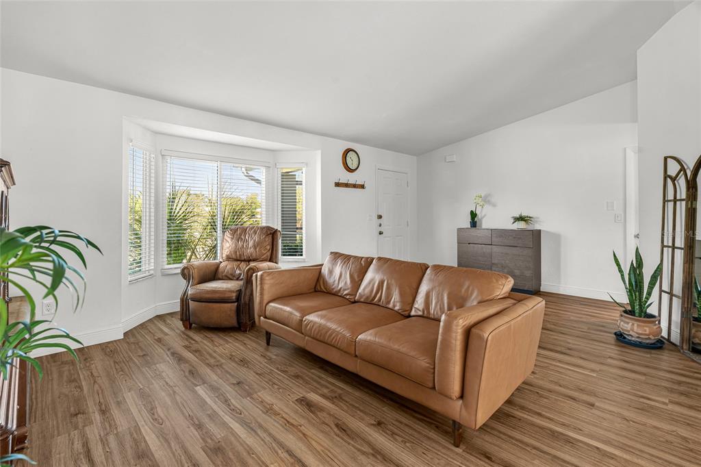 A living room features a tan leather sofa, a recliner, and wood-look flooring — 2600 PALMETTO STREET, NOKOMIS, FL