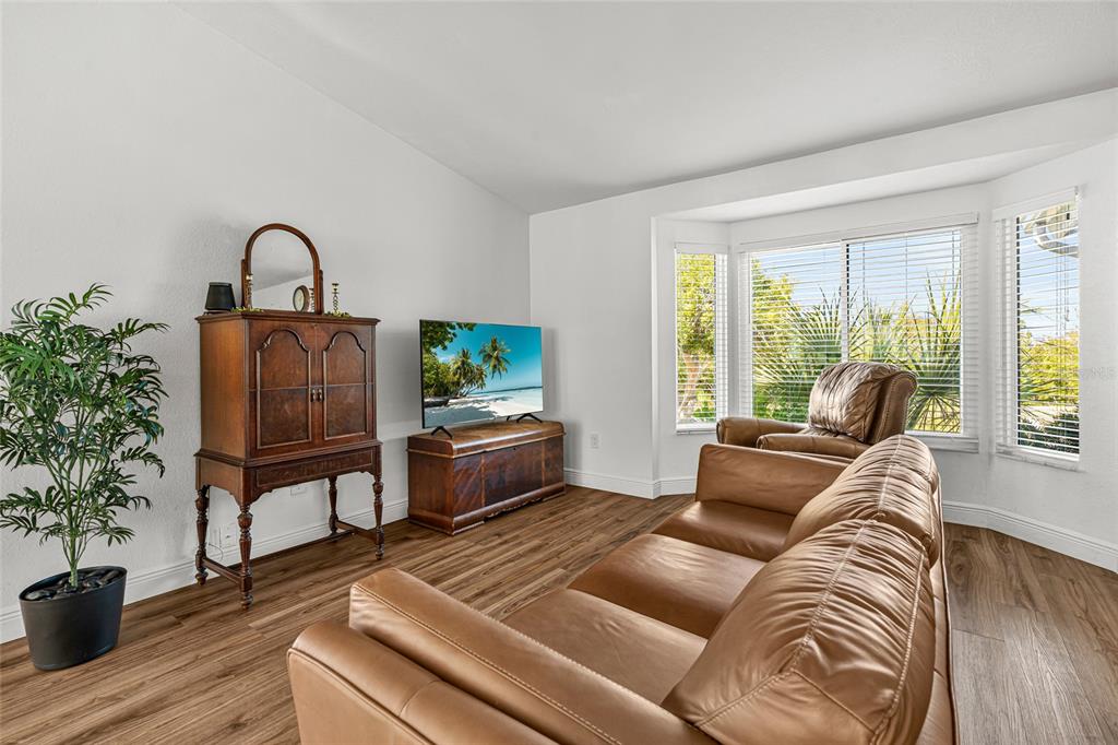A living room features a leather sofa, a television on a wooden chest, and windows — 2600 PALMETTO STREET, NOKOMIS, FL