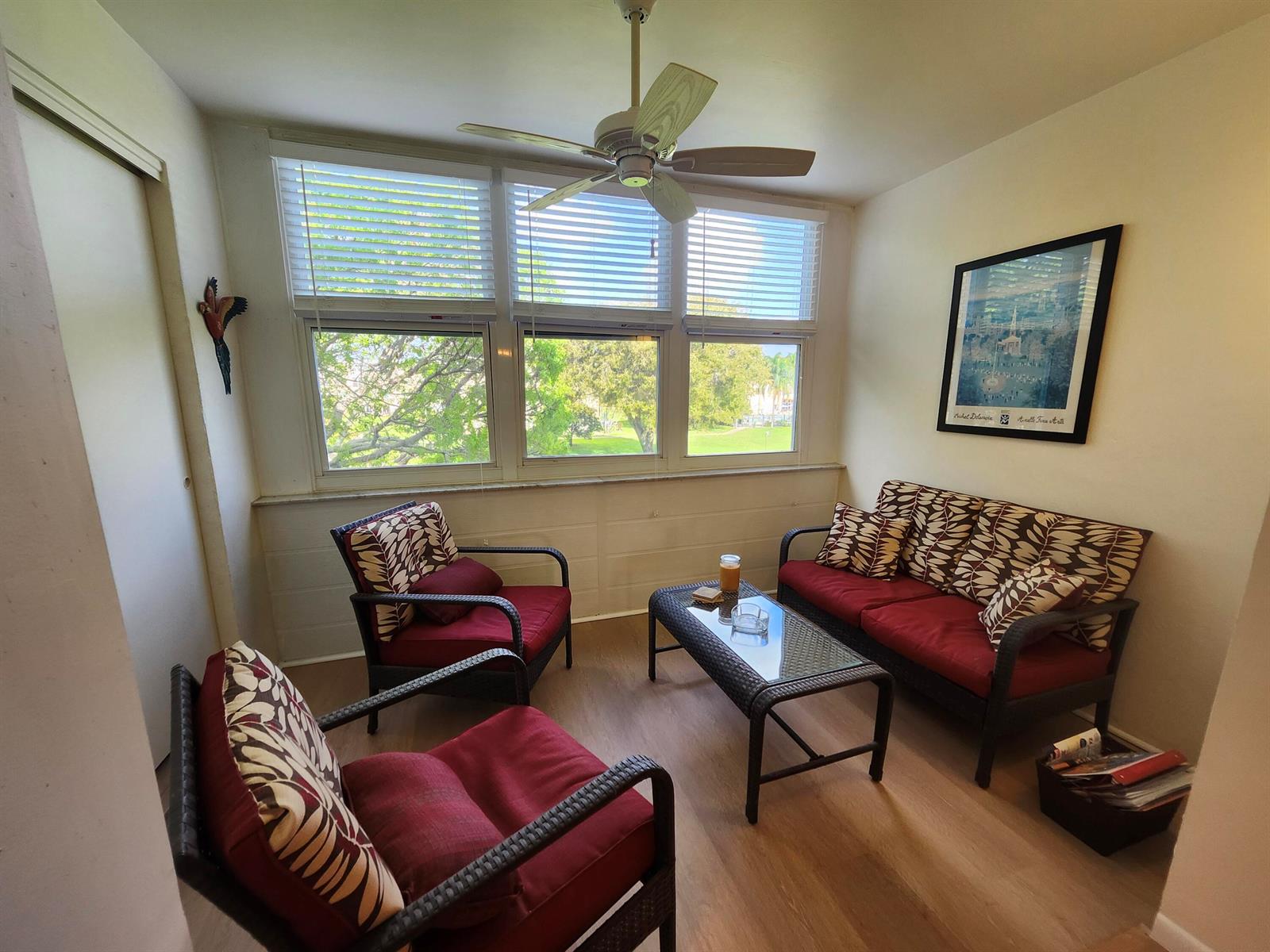 A sunroom features wicker furniture with red cushions, a glass-top coffee table, and large windows — 2600 NE 1st Lane # 311, Boynton Beach FL 33435, BOYNTON BEACH, FL