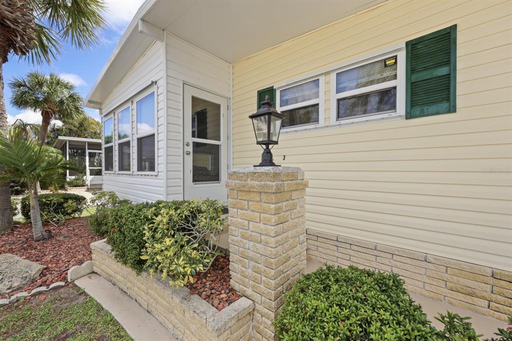 A yellow house exterior features a brick pillar, a lantern, and green window shutters — 2100 KINGS HIGHWAY UNIT 840, PORT CHARLOTTE, FL