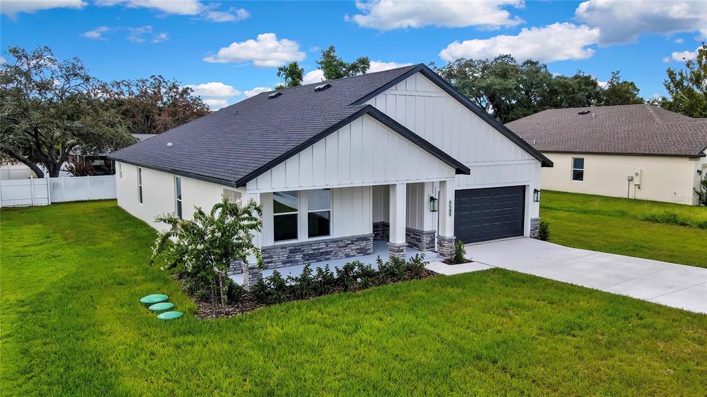 A single-story house with white vertical siding, stone accents, and a dark shingled roof — 6589 FREEPORT DRIVE, SPRING HILL, FL