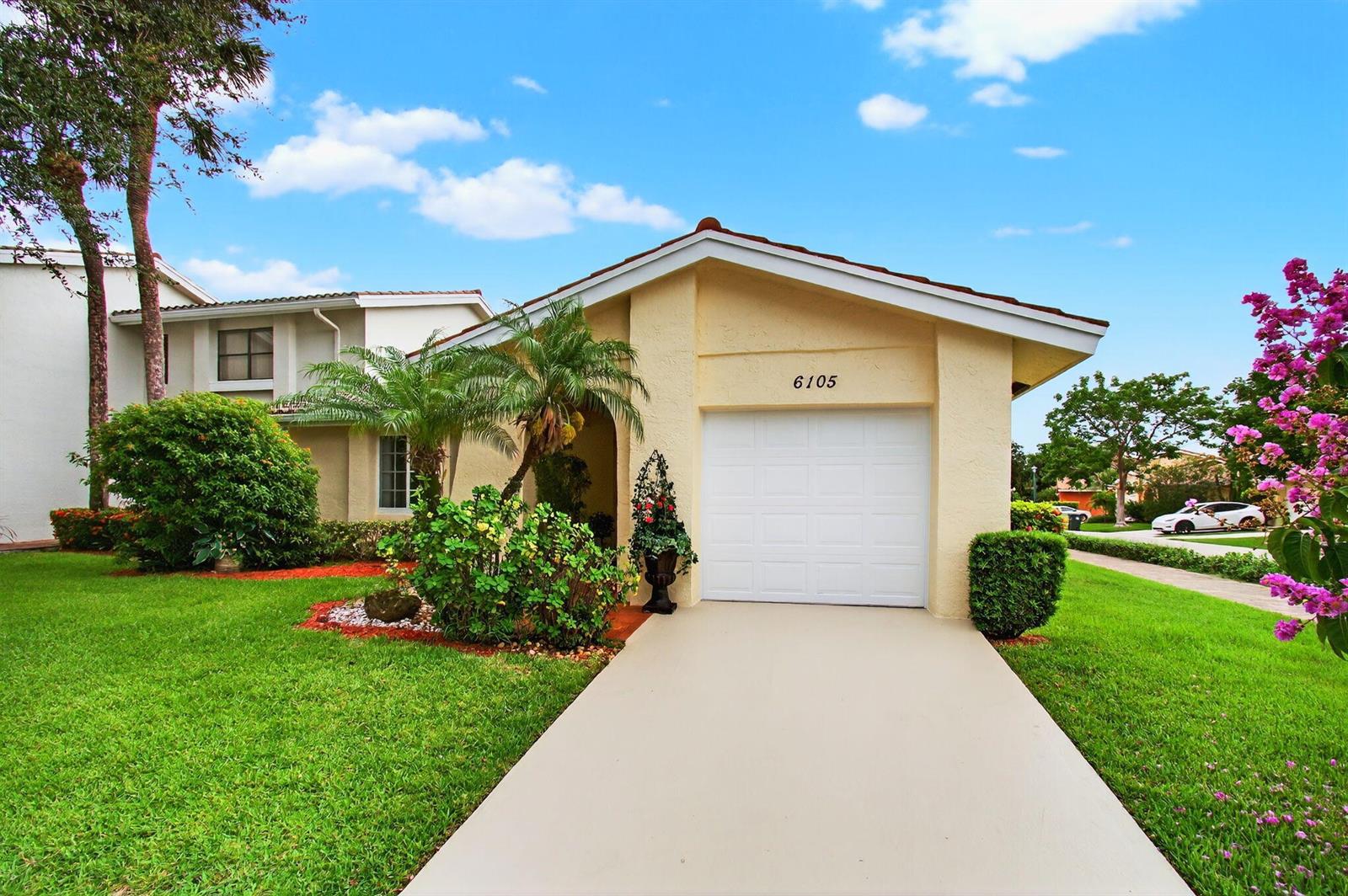 A single-story house with a white garage door, tan stucco exterior, and a green lawn — 6105 Via Laguna Lane, Boca Raton FL 33433, BOCA RATON, FL