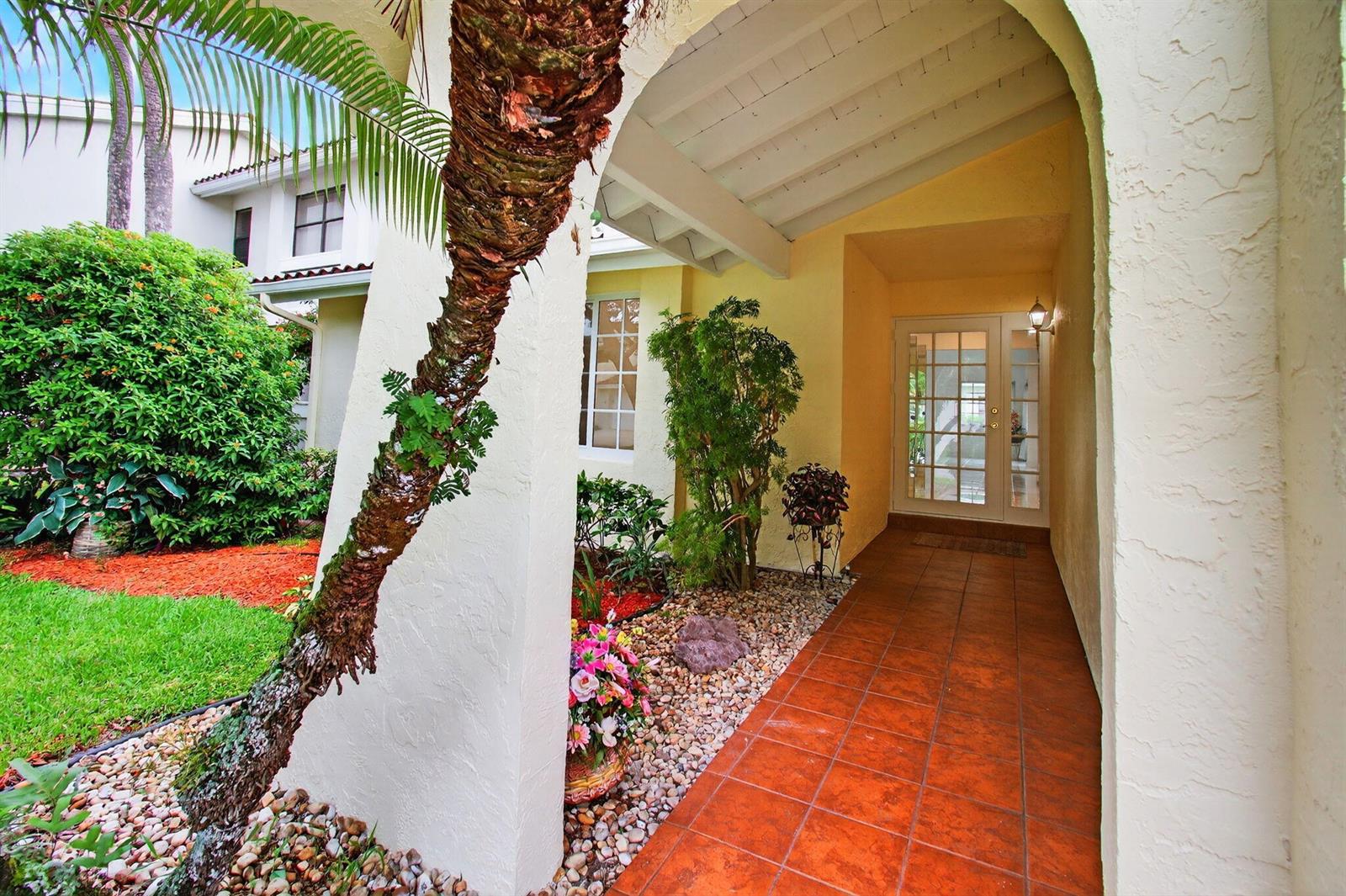 A covered entryway with a tiled floor leads to a white-framed glass front door — 6105 Via Laguna Lane, Boca Raton FL 33433, BOCA RATON, FL