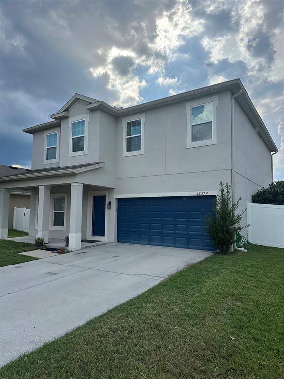 A two-story house features a blue garage door, a covered porch, and a concrete driveway — 12372 STONE BARK TRAIL, ORLANDO, FL