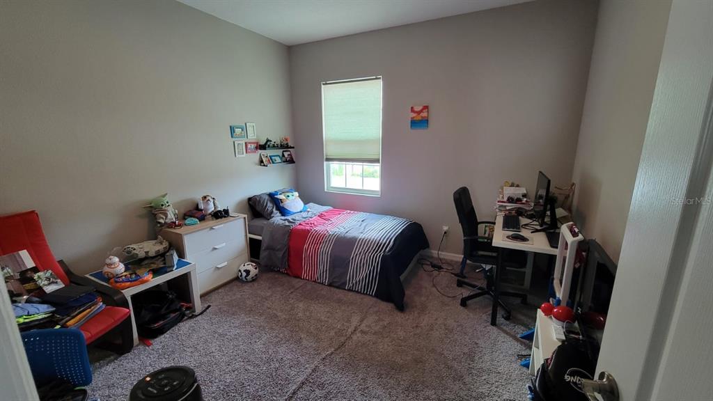 A bedroom features a single bed, a desk with a computer, and a dresser — 12372 STONE BARK TRAIL, ORLANDO, FL