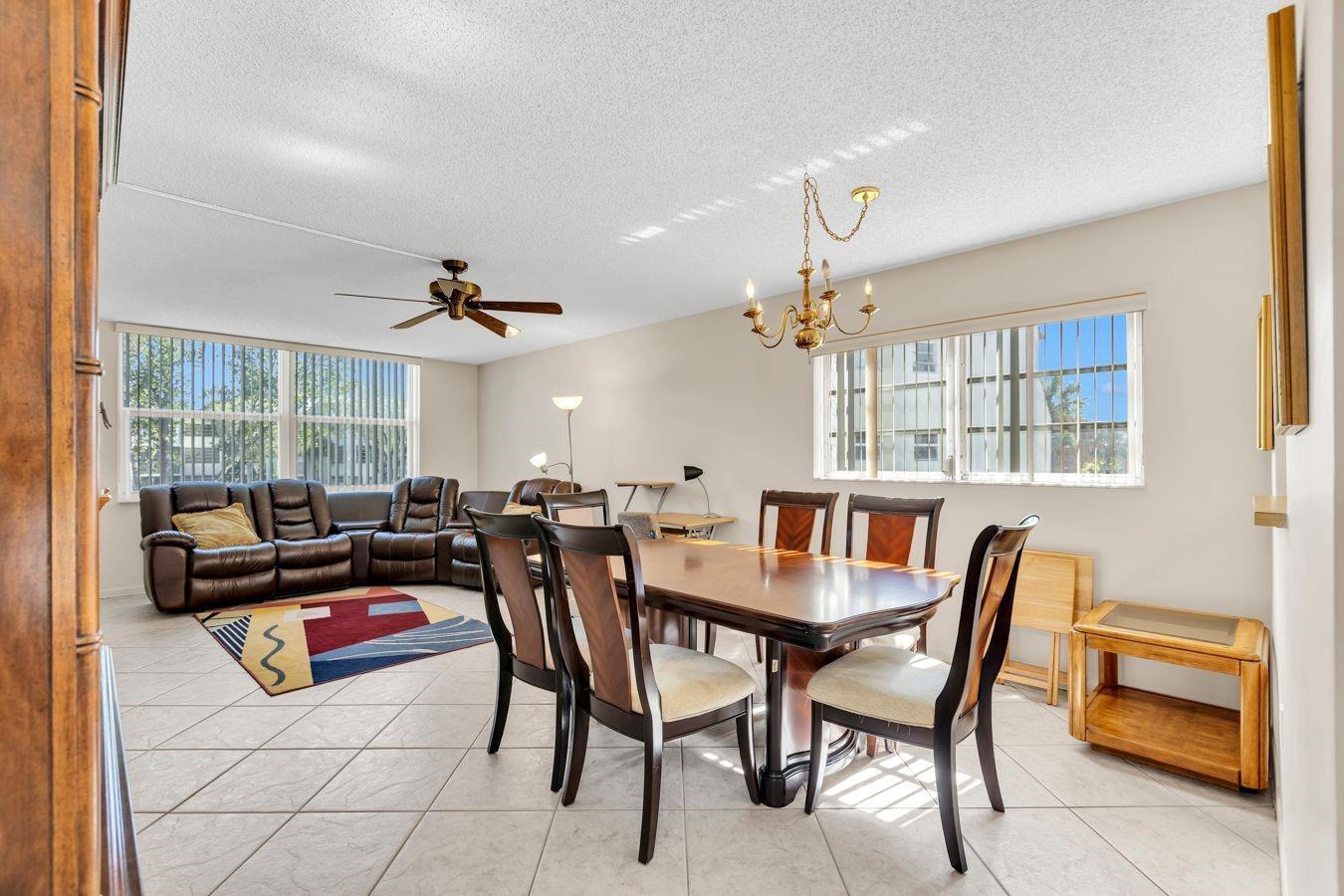 A dining area with a wooden table and chairs sits adjacent to a living room — 6850 Royal Palm Boulevard # 212, Margate FL 33063, MARGATE, FL