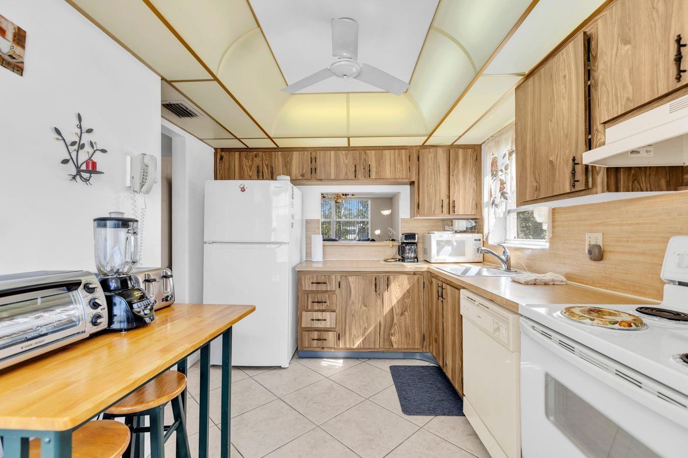 A kitchen with wood cabinets, white appliances, a ceiling fan, and a breakfast bar — 6850 Royal Palm Boulevard # 212, Margate FL 33063, MARGATE, FL