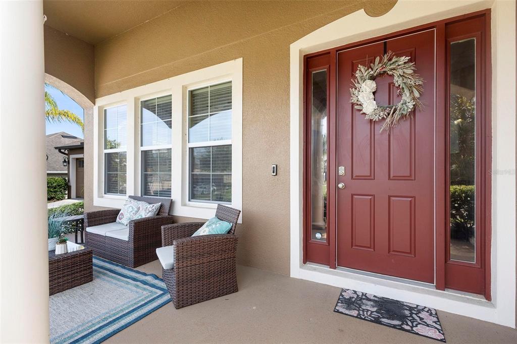 A covered front porch features a red door with a wreath and two wicker chairs — 3551 STATHAM DRIVE, APOPKA, FL