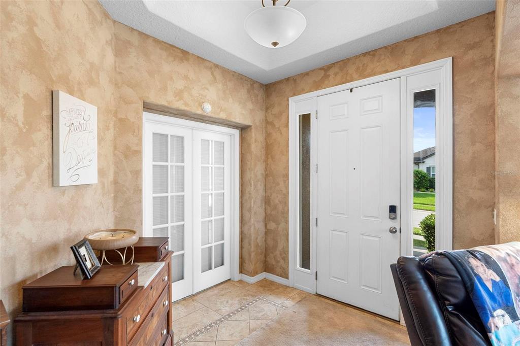 An entryway features a white front door, French doors, tile flooring, and textured tan walls — 3551 STATHAM DRIVE, APOPKA, FL