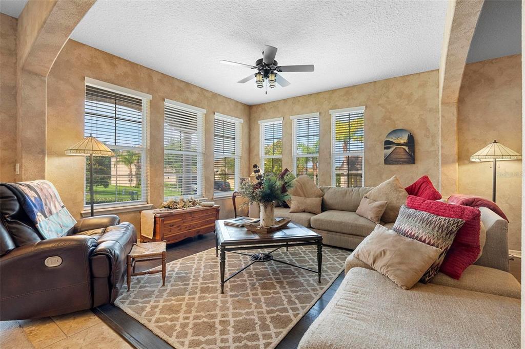 A living room features a leather recliner, a sectional sofa, and large windows with blinds — 3551 STATHAM DRIVE, APOPKA, FL