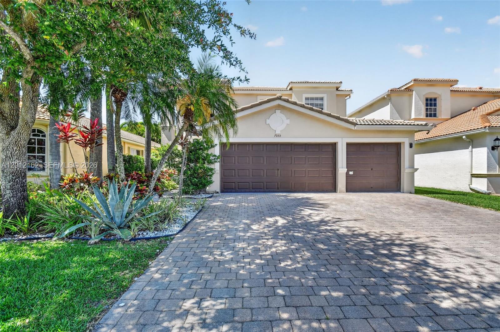 A two-story suburban house features a three-car garage and a paved driveway — 7055 Via Leonardo, Lake Worth FL 33467, LAKE WORTH, FL