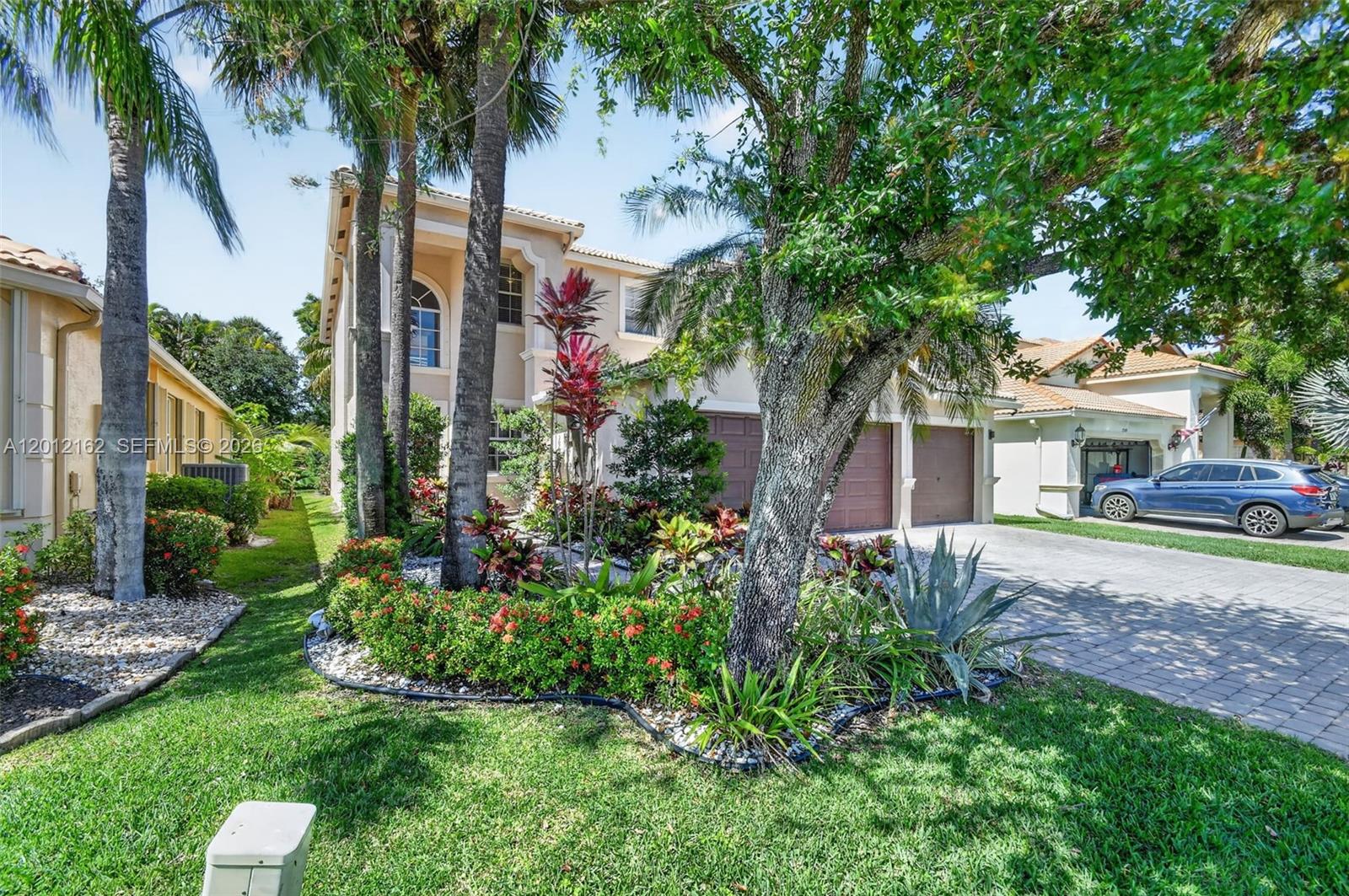 A two-story house features a paved driveway, a two-car garage, and lush front landscaping — 7055 Via Leonardo, Lake Worth FL 33467, LAKE WORTH, FL