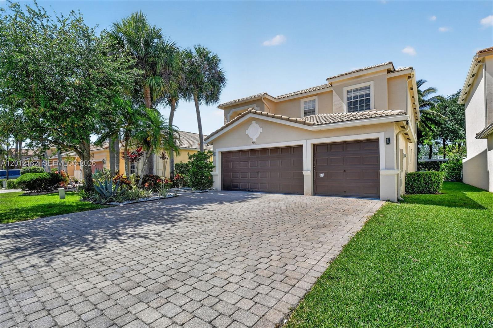 A two-story beige house features a two-car garage and a paved driveway — 7055 Via Leonardo, Lake Worth FL 33467, LAKE WORTH, FL