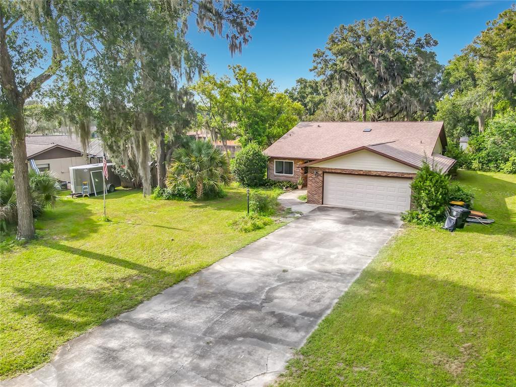 A single-story brick house with a two-car garage and a concrete walkway at dusk — 474 W OAKWOOD AVENUE, ORANGE CITY, FL