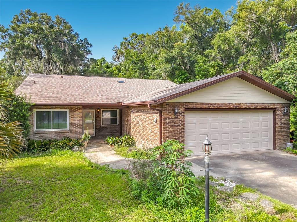 A single-story brick house with a two-car garage and a long concrete driveway — 474 W OAKWOOD AVENUE, ORANGE CITY, FL