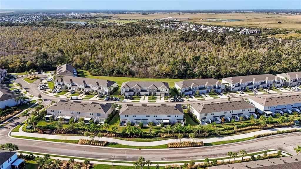 An aerial view of a suburban neighborhood featuring multiple rows of townhomes and surrounding greenery — 9052 DRIVEN SNOW STREET, SARASOTA, FL