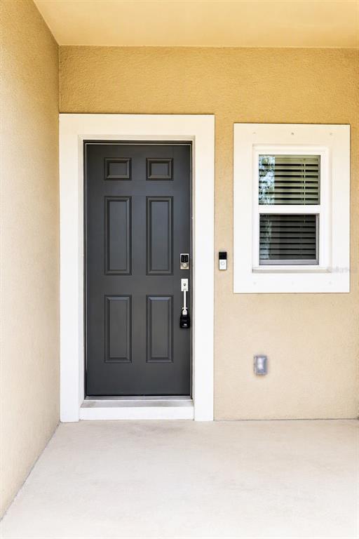 A dark gray front door with a white frame sits beside a window on a porch — 9052 DRIVEN SNOW STREET, SARASOTA, FL