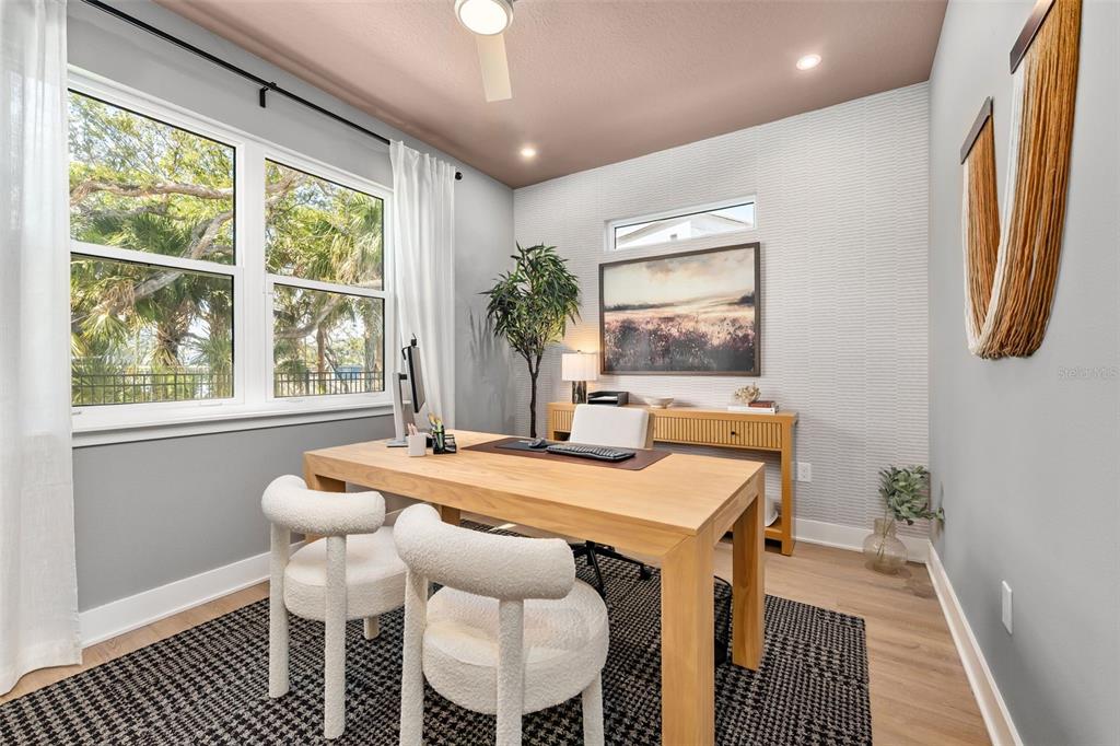 A home office features a wooden desk, two white chairs, and a textured accent wall — 2111 TIDEWATCH LOOP, NEW SMYRNA BEACH, FL