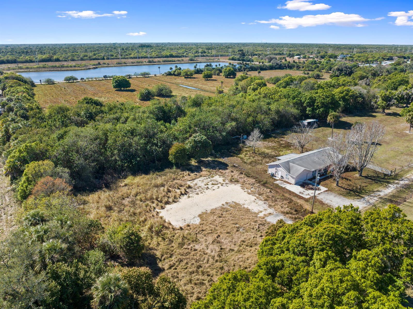 An aerial view shows a house on a large, grassy lot near a lake — 6406 Oleander Avenue, Fort Pierce FL 34982, FORT PIERCE, FL