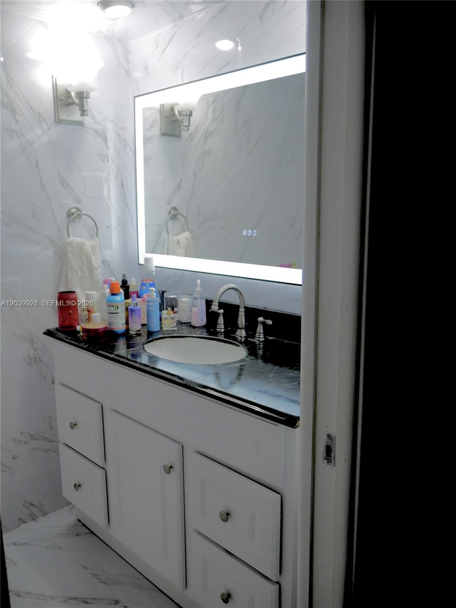 A bathroom features a white vanity, black countertop, and a large rectangular LED mirror — 3001 S Course Dr # 508, Pompano Beach FL 33069, POMPANO BEACH, FL