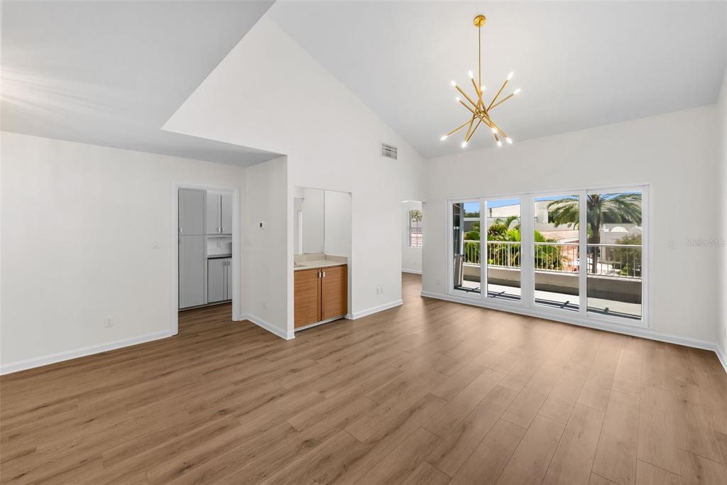 A bright room with vaulted ceilings, light wood floors, a gold chandelier, and sliding glass doors — 1647 W SNOW CIRCLE UNIT 204, TAMPA, FL