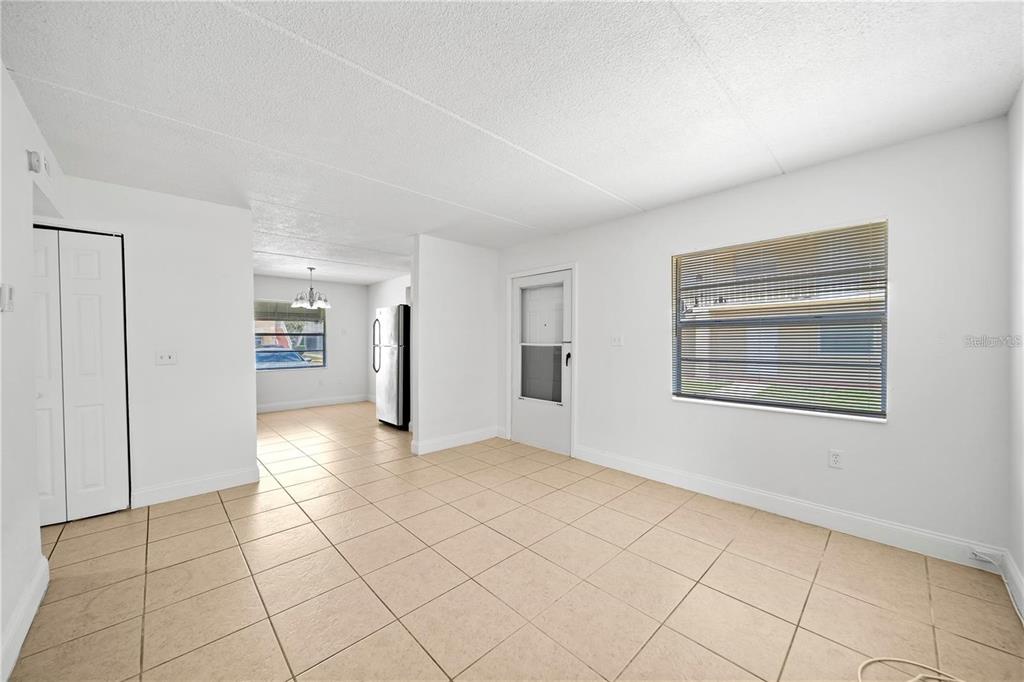 A bright room with beige tile flooring, white walls, a window, and a doorway — 702 MICHIGAN COURT UNIT 1, ST CLOUD, FL