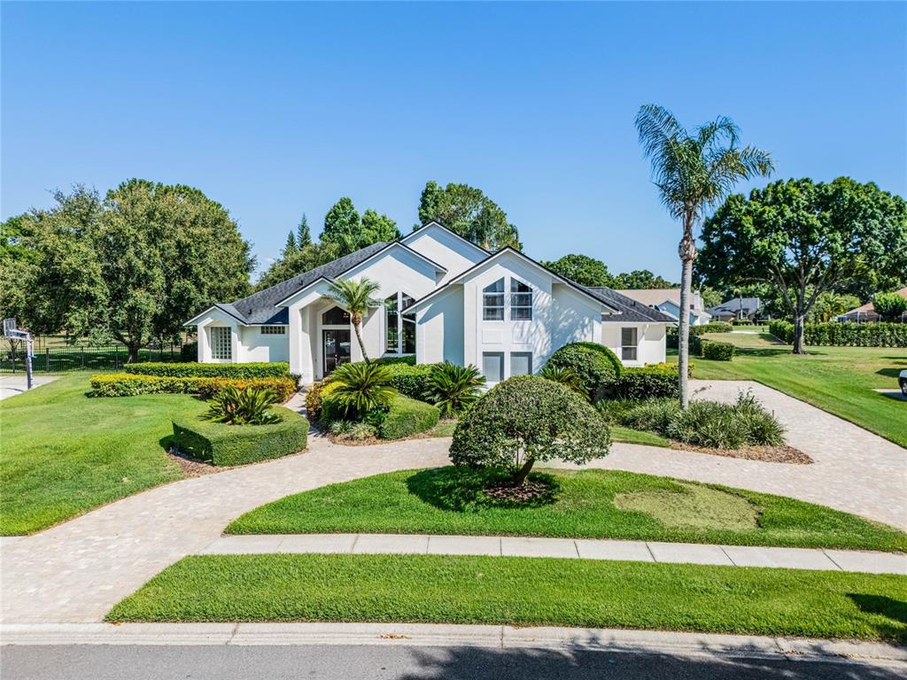 A white single-story house with a paved driveway and landscaped lawn under a clear sky — 2031 WILLOW LAUREN LANE UNIT L, WINDERMERE, FL