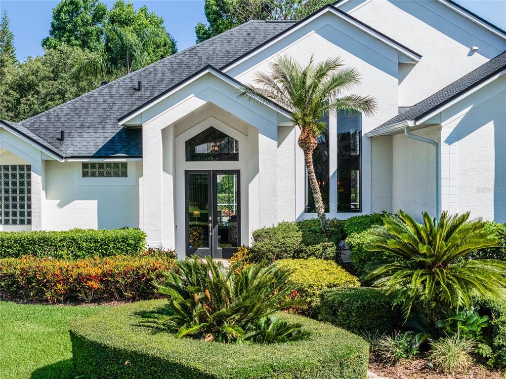 The exterior of a white house features a dark double-door entrance and a palm tree — 2031 WILLOW LAUREN LANE UNIT L, WINDERMERE, FL