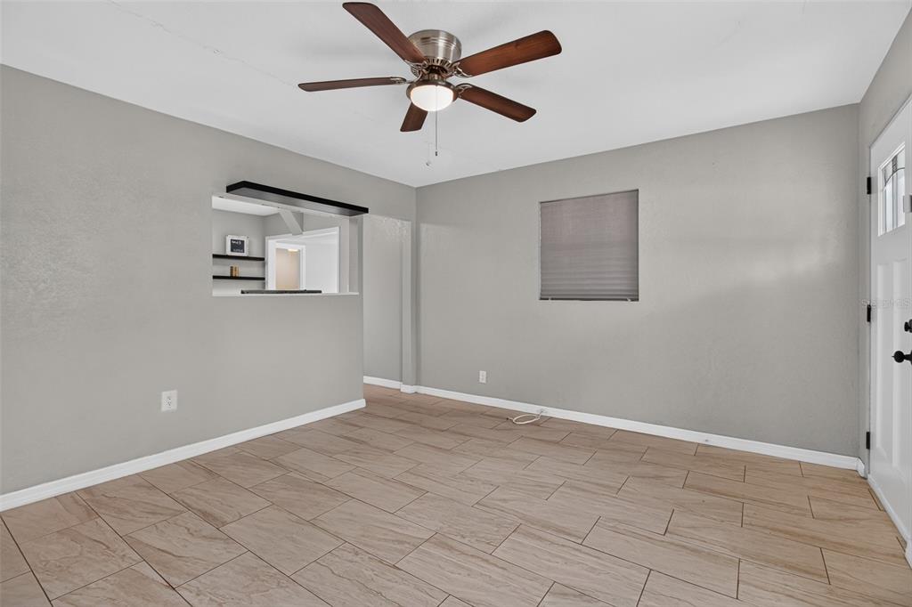 A living room with gray walls, light wood-look tile flooring, and a ceiling fan — 4529 73RD STREET N, ST PETERSBURG, FL