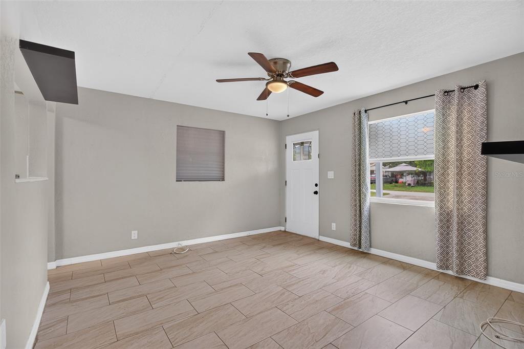 An empty room features light gray walls, wood-look tile flooring, a ceiling fan, and a door — 4529 73RD STREET N, ST PETERSBURG, FL