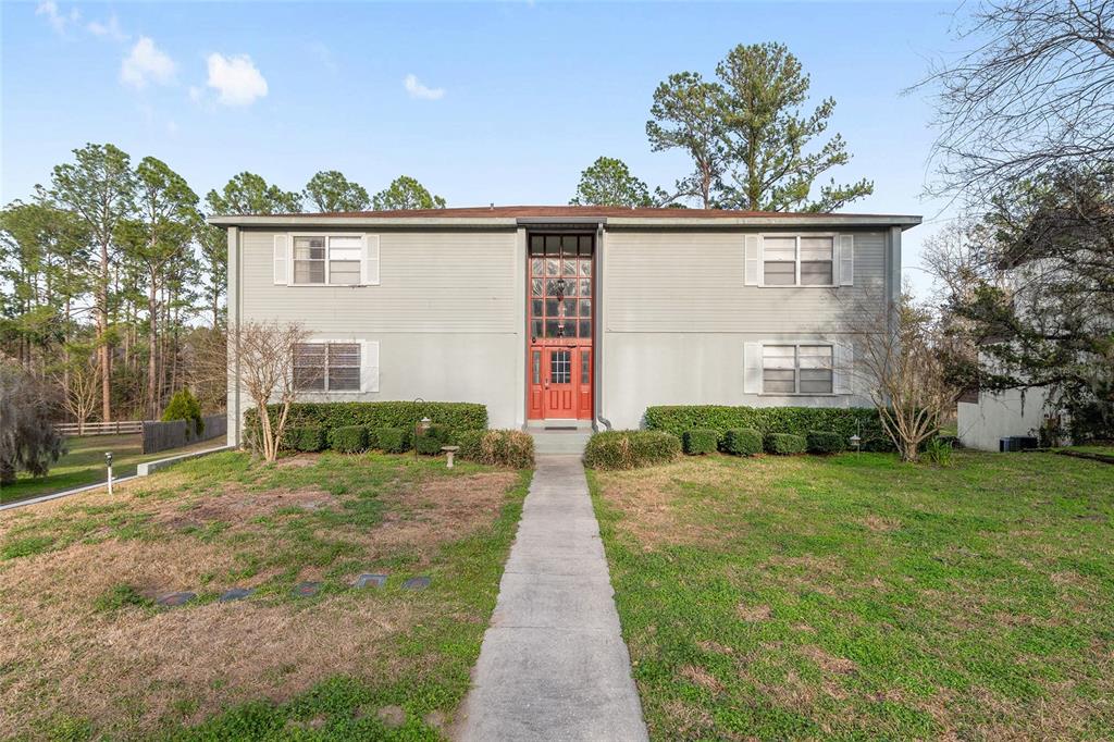 A two-story house with light gray siding, a red front door, and a central window panel — 2715 NW 104TH COURT UNIT 1, GAINESVILLE, FL