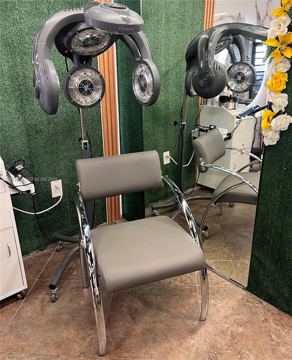 A salon chair sits beneath a professional hair dryer in a room with green walls — 1576 NE 205th ter, Miami FL 33179, MIAMI, FL