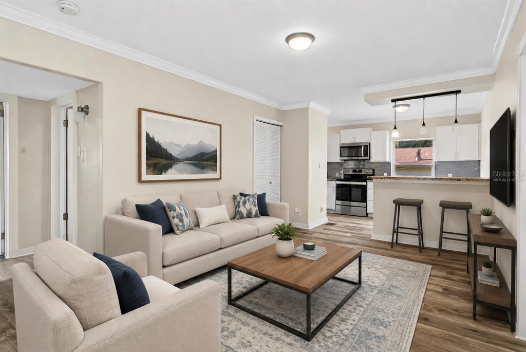 A living room with a sofa, coffee table, and an open kitchen with bar seating — 205 E FOUNTAIN STREET, FRUITLAND PARK, FL