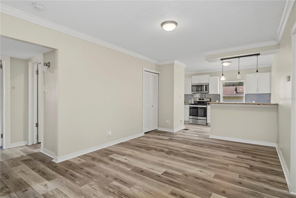 A dining area with wood-look flooring leads to an open kitchen with white cabinets — 205 E FOUNTAIN STREET, FRUITLAND PARK, FL