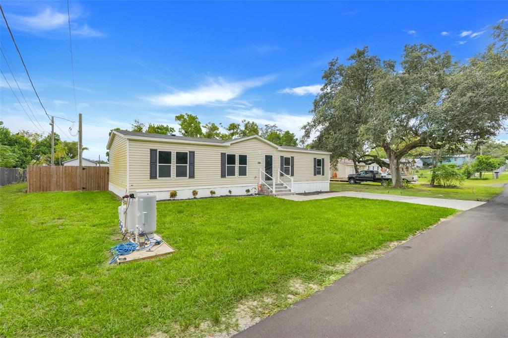 A light yellow manufactured home sits on a grassy lot next to a paved driveway — 3417 CARTER ROAD, HAINES CITY, FL