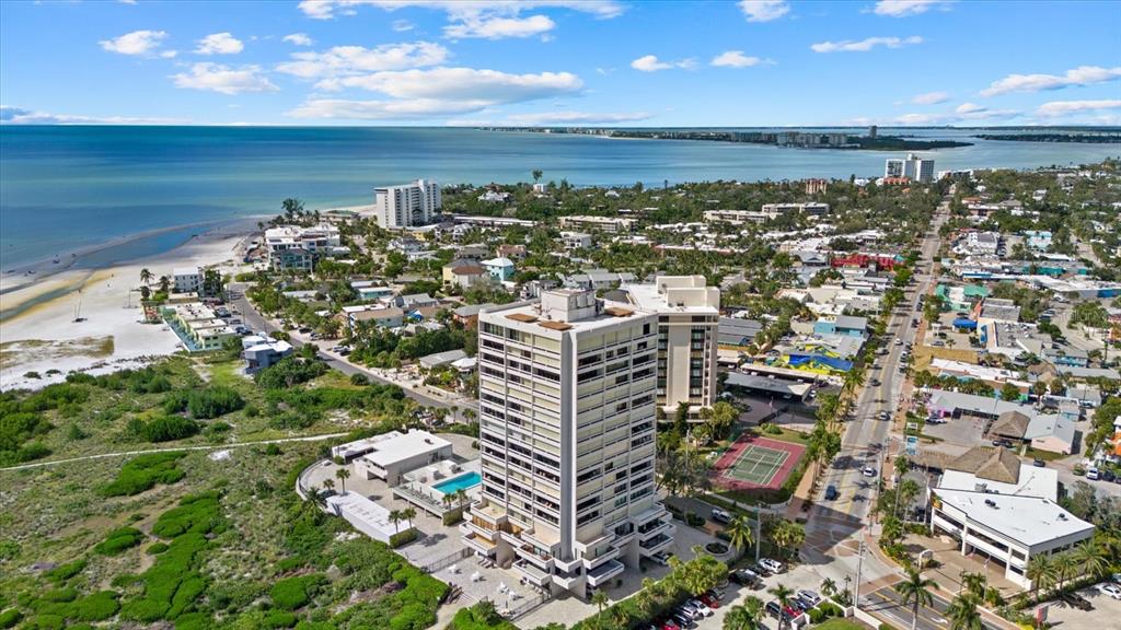 An aerial view shows a high-rise condominium building near a beach and coastal town — 5400 OCEAN BOULEVARD UNIT 9-4, SARASOTA, FL