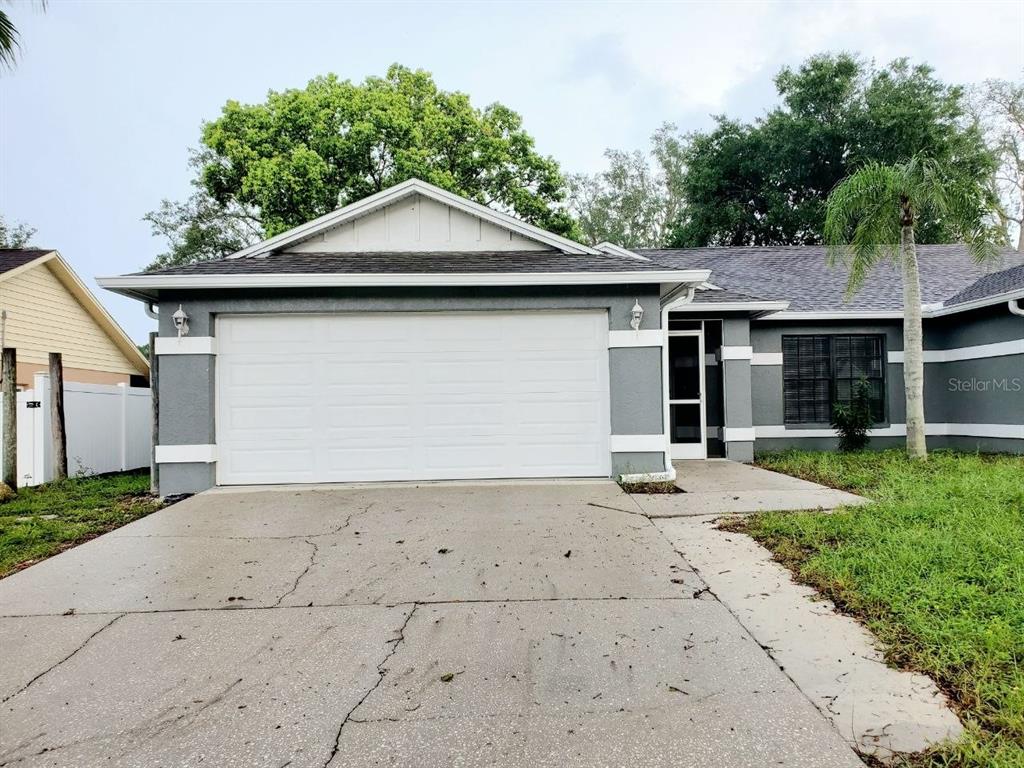 A gray single-story house features a two-car garage, a concrete driveway, and a palm tree — 7432 CANVASBACK DRIVE, NEW PORT RICHEY, FL