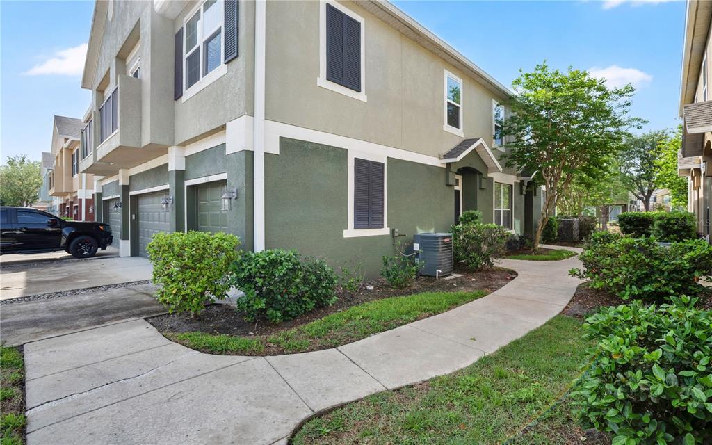 A two-story townhouse exterior with a green stucco facade, garage, and a concrete walkway — 3031 SAN JACINTO CIRCLE UNIT 3031, SANFORD, FL
