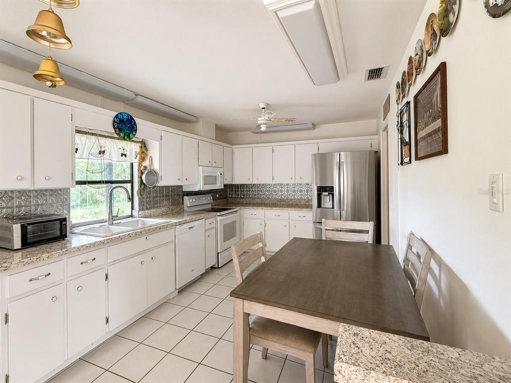 A living and dining area features tile flooring, a vaulted ceiling, and a brown sofa — 3488 DWIGHT STREET, PORT CHARLOTTE, FL