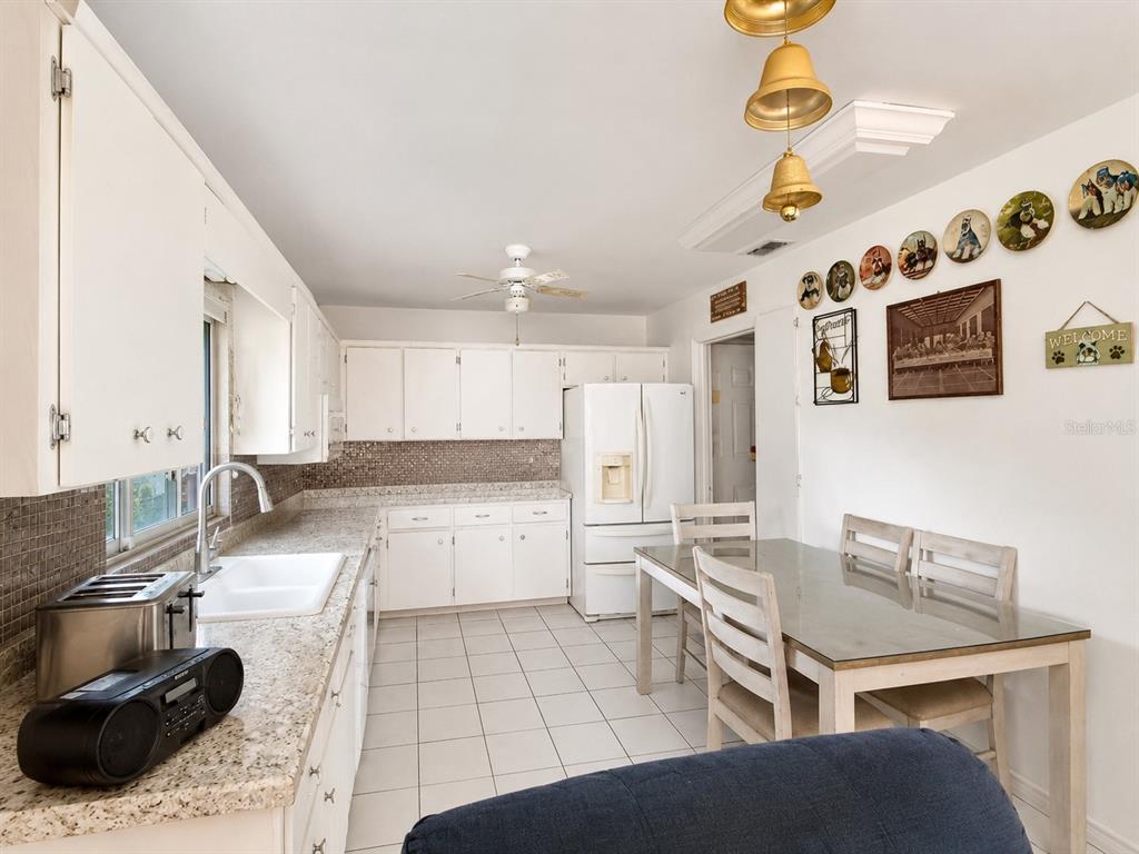 A kitchen with white cabinets, granite countertops, a dining table, and tiled flooring — 3488 DWIGHT STREET, PORT CHARLOTTE, FL