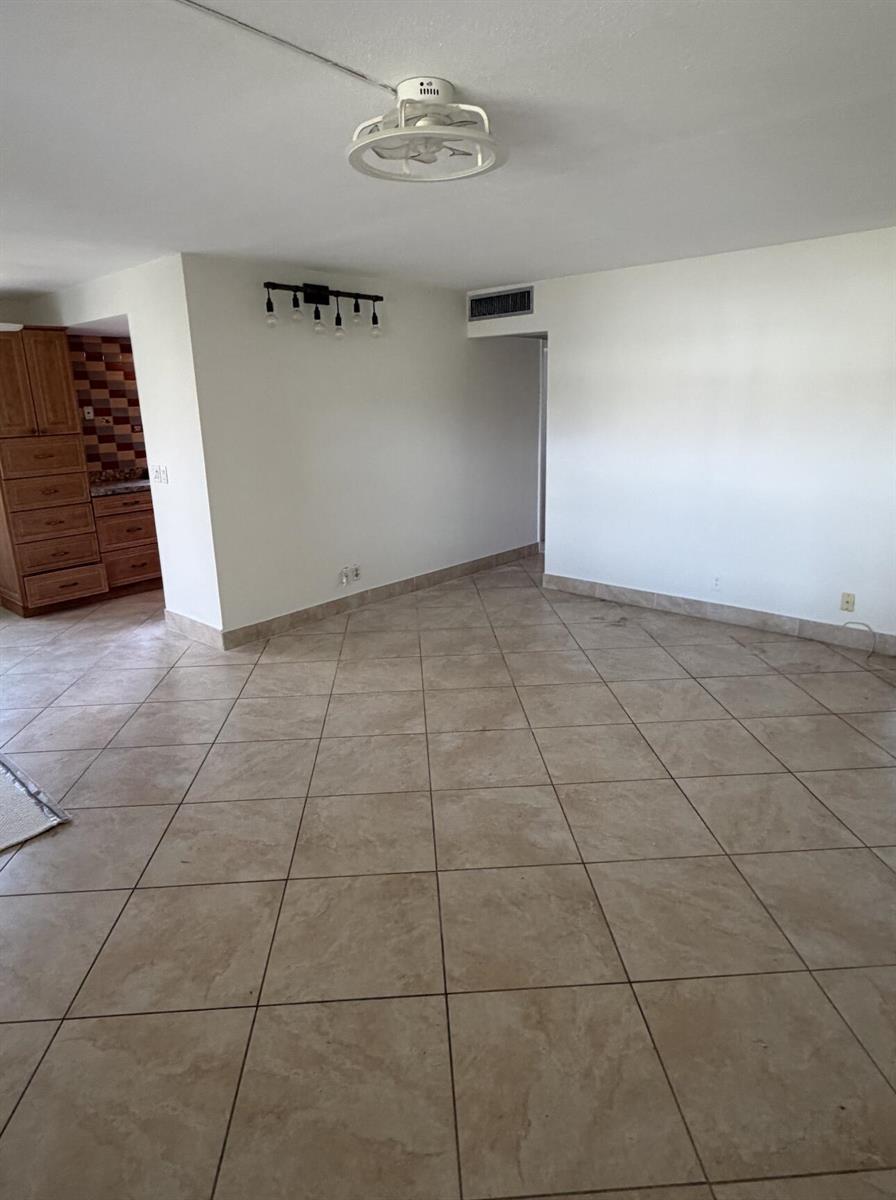 An empty living area features beige tile flooring, white walls, and a ceiling fan — 157 Saxony D, Delray Beach FL 33446, DELRAY BEACH, FL