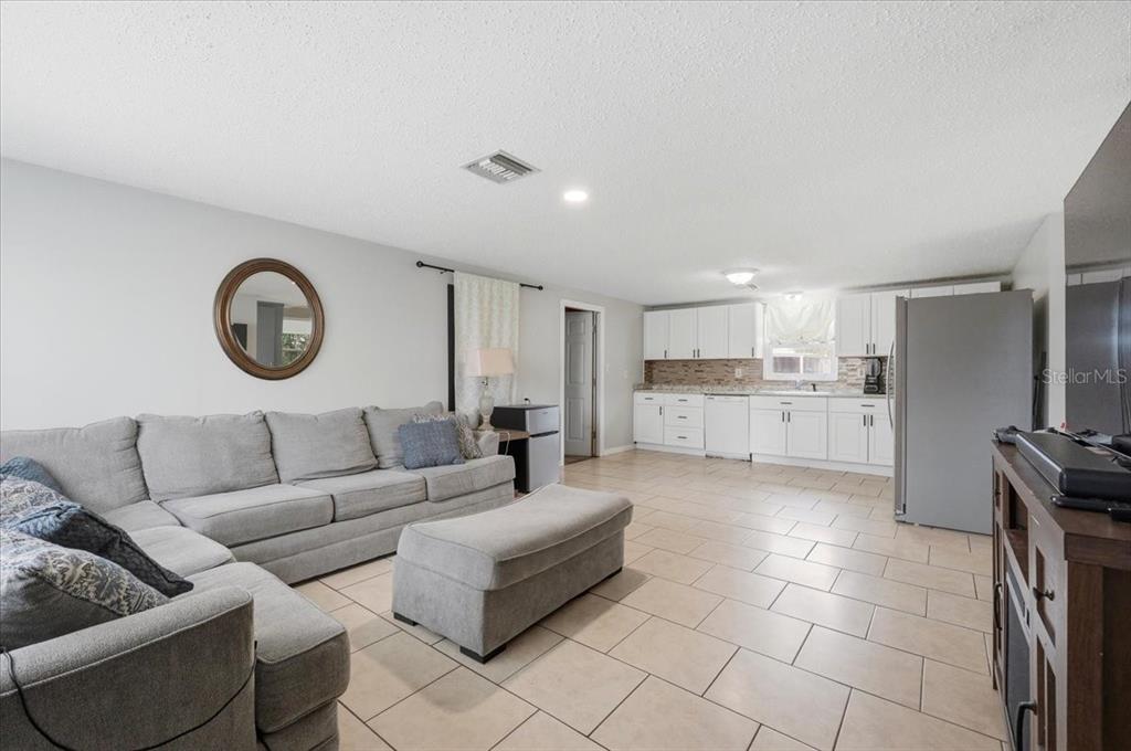 A living room with a gray sectional sofa flows into an open kitchen with white cabinets — 2991 W VERONA ROAD, AVON PARK, FL