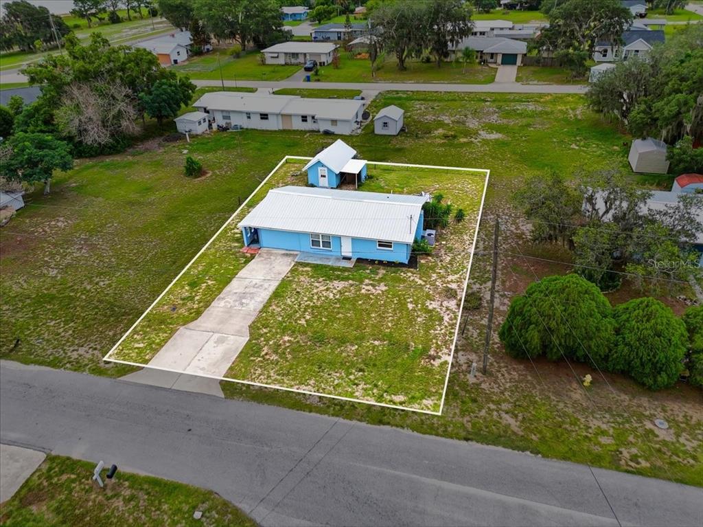 An aerial view shows a blue house with a white roof on a grassy lot — 2991 W VERONA ROAD, AVON PARK, FL