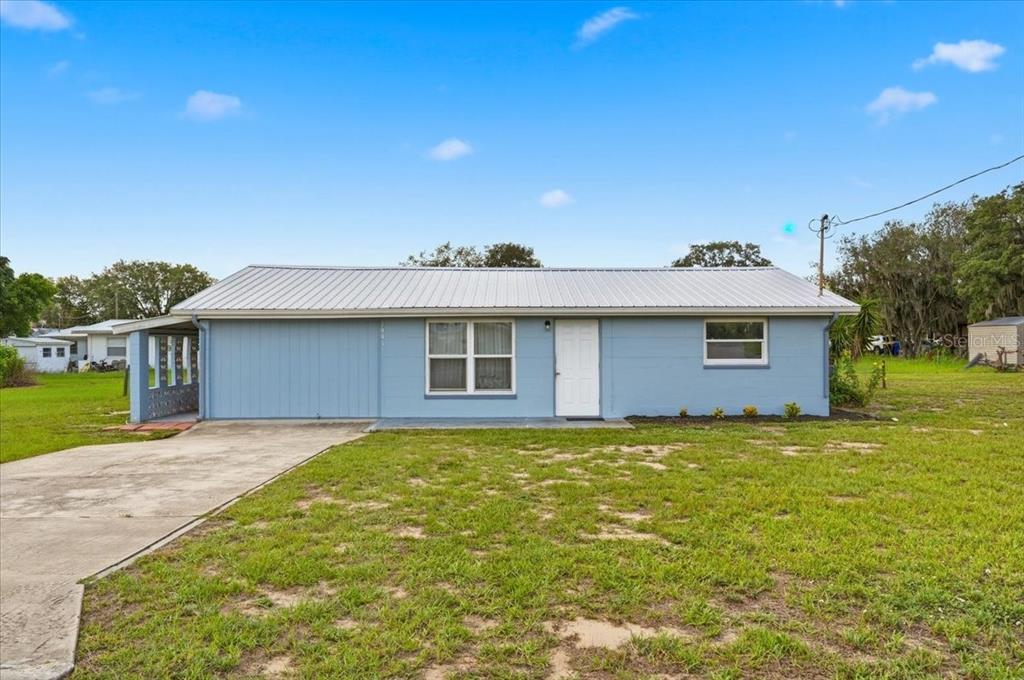 A single-story light blue house with a metal roof and a concrete driveway — 2991 W VERONA ROAD, AVON PARK, FL